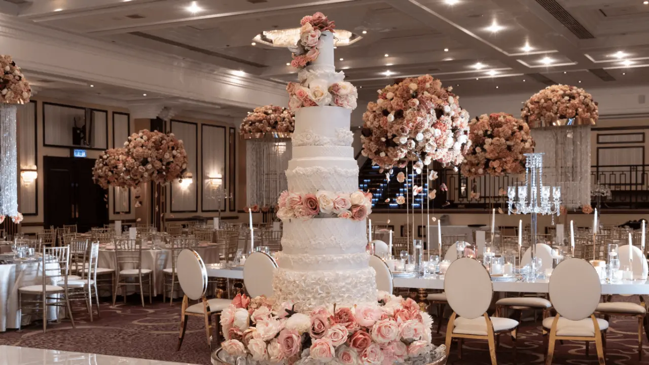 A breathtaking wedding reception setup at the National Motorcycle Museum, featuring a towering wedding cake, floral arrangements, and a beautifully decorated ballroom.