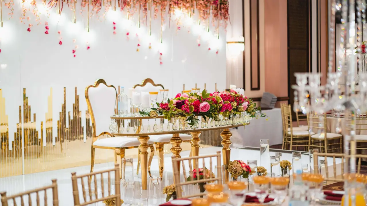 A beautifully decorated head table with gold chairs, a floral centerpiece, and a romantic backdrop. This image showcases the elegance of the National Motorcycle Museum as a wedding venue.