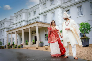 Bride and groom in traditional Indian attire posing outside a grand venue, captured by an expert Indian wedding photographer.