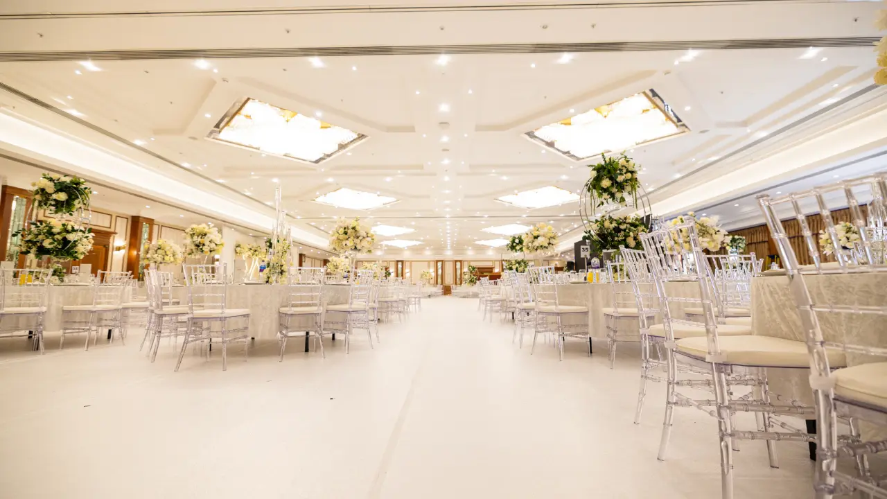 A wedding reception at the National Motorcycle Museum, featuring a tiered wedding cake with pink flowers and a decorated ballroom.