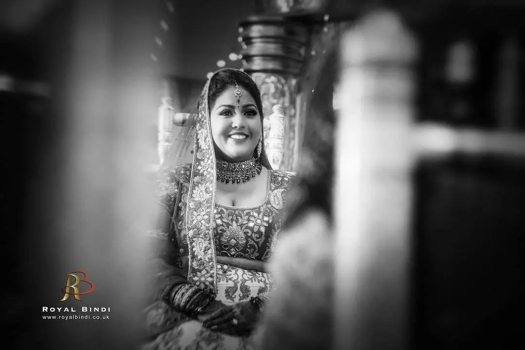 Candid black-and-white portrait of a joyful bride, showcasing her traditional wedding look and radiant smile.