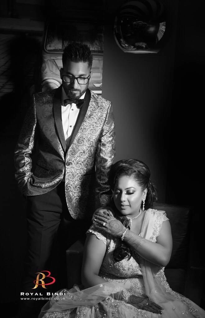 Artistic black-and-white portrait of a couple, showcasing intricate henna designs and elegant wedding attire.