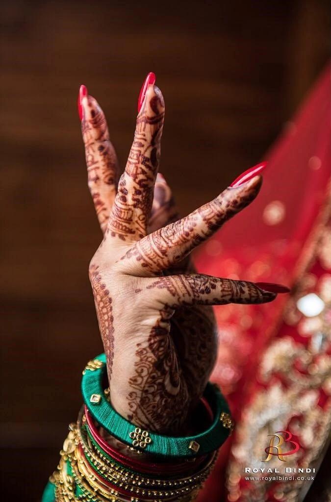Close-up of a bride’s henna-adorned hand with colorful bangles, captured during a Gujarati pre-wedding session.