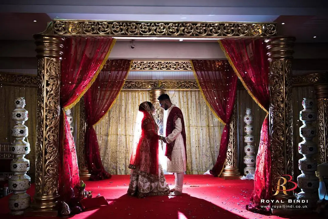 A bride and groom sharing a romantic moment under the mandap, beautifully captured during a Gujarati wedding in the UK.